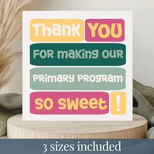 May include: A white card with colorful text that reads "Thank You For Making Our Primary Program So Sweet!" The text is in yellow, pink, teal, and green. The card is on a wooden stand.