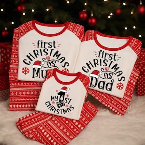 May include: Matching Christmas pajamas sets in red and white. The tops have raglan sleeves and the text "First Christmas as Mum", "First Christmas as Dad", and "My 1st Christmas". The bottoms have a red and white pattern.