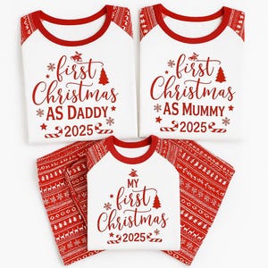 May include: Matching family Christmas pajamas in white and red. The shirts have red sleeves and collars, with the text "first Christmas" and "2025". The pants are red with a white pattern. One shirt says "AS DADDY", another says "AS MUMMY", and the third says "MY".