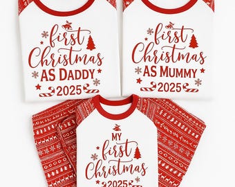 May include: A set of matching family Christmas pyjamas in white and red. The shirts have red sleeves and collars, with the text "first Christmas" and "2025". The trousers are red with a white pattern. One shirt says "AS DADDY", another says "AS MUMMY", and the third says "MY".