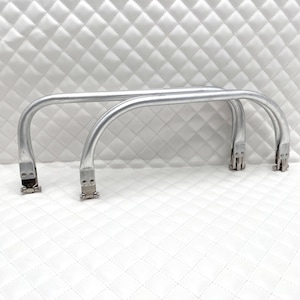 May include: Two silver metal handles with a curved shape and a silver metal clasp at each end.