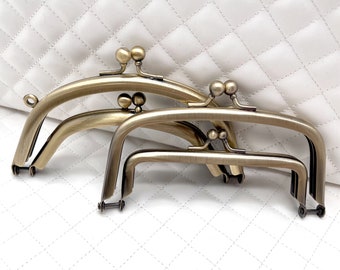 May include: Three antique brass purse frames of different sizes. The frames are stacked on top of each other, with the largest frame on the bottom and the smallest frame on top.