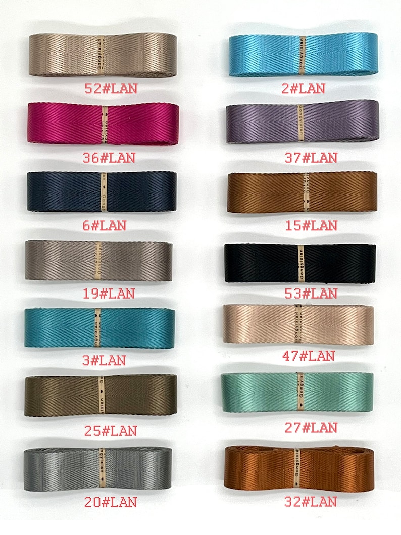 May include: A collection of 12 different coloured ribbon spools with numbers and the text "#LAN" printed on each spool.