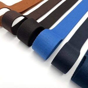 May include: Six different colors of cotton webbing, including brown, black, blue, and navy. The webbing is rolled up and arranged in a fan shape.