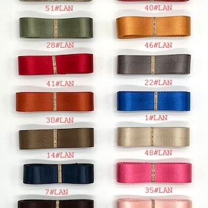 May include: A collection of 15 different coloured ribbon samples, each with a unique number and the text "#LAN" printed on them. The ribbons are arranged in two rows of seven and one row of one.