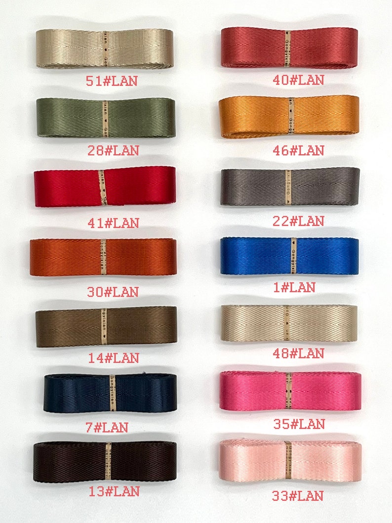 May include: A collection of 15 different coloured ribbon samples, each with a unique number and the text "#LAN" printed on them. The ribbons are arranged in two rows of seven and one row of one.