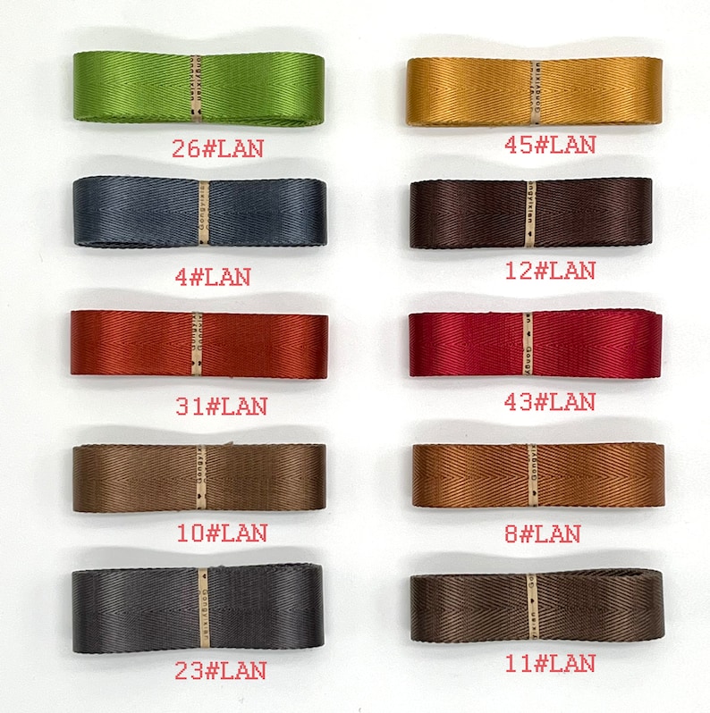 May include: A collection of ten different coloured ribbon samples, each with a number and the text "#LAN" printed on a white label. The ribbons are arranged in two rows of five, with the numbers increasing from left to right.