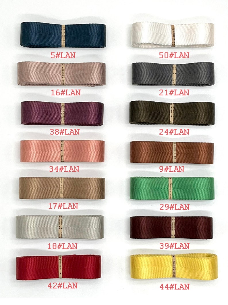May include: A collection of 12 different coloured ribbon spools with numbers and the text "#LAN" printed on each spool.