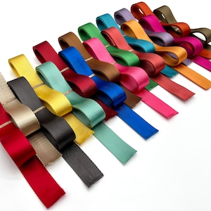 May include: A collection of 20 different coloured ribbon trims with a subtle gold thread running through each one. The ribbons are arranged in a fan shape on a white background.