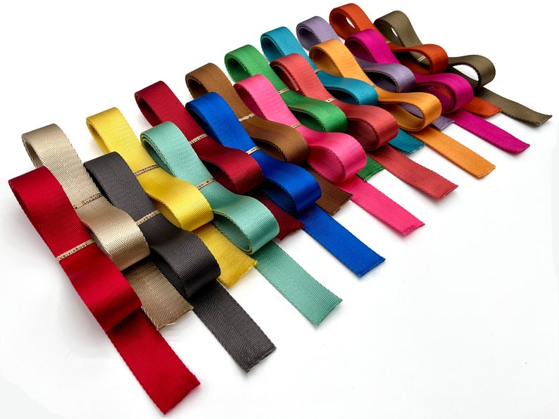 May include: A collection of 20 different coloured ribbon trims with a subtle gold thread running through each one. The ribbons are arranged in a fan shape on a white background.