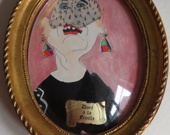 May include: A framed oval portrait of a woman wearing a black hat and a veil. The portrait is painted in watercolor and has a gold frame. The text "Doré à la Feuille" is written on a scroll at the bottom of the portrait.