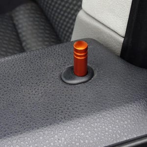 Könnte beinhalten: Orangener Türgriff zum Ziehen für ein Auto. Der Griff ist aus Metall und hat eine runde Form.