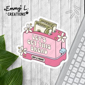 May include: A pink sticker featuring a retro-style toaster with the text "LET'S GET THIS BREAD." The toaster has money sticking out of it, with floral and star accents. The words "HOT & FRESH" are also visible.