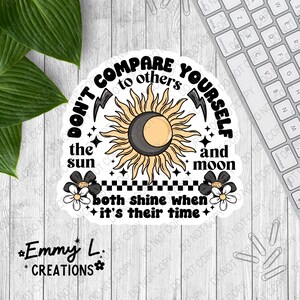 May include: A black and white sticker with a sun and moon graphic and the text "Don't compare yourself to others the sun and moon both shine when it's their time".