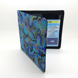 May include: A blue and gold patterned fabric wallet with a clear plastic window for displaying a parking card for disabled people. The card reads "Parking Card for Disabled People" and "UK".