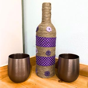 Geüpcycled wijnfles met jutegaren, lint en bloemversieringen