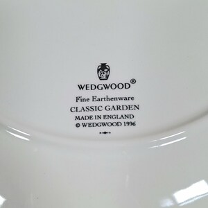 K&ouml;nnte beinhalten: Nahaufnahme eines wei&szlig;en Tellers mit dem WEDGWOOD-Logo und Text. Der Text lautet "Fine Earthenware CLASSIC GARDEN MADE IN ENGLAND &copy; WEDGWOOD 1996". Der Teller hat eine gl&auml;nzende Oberfl&auml;che.