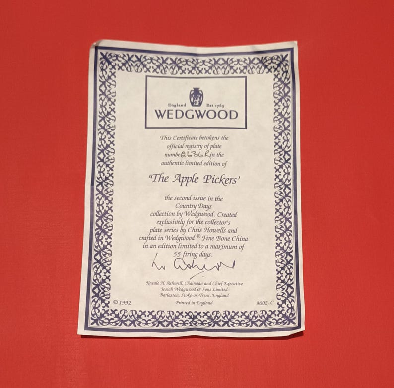 Pode incluir: Um certificado de autenticidade para um prato Wedgwood "The Apple Pickers". O certificado &eacute; branco com uma borda preta e apresenta o logotipo da Wedgwood. O texto no certificado indica que o prato faz parte da cole&ccedil;&atilde;o Country Days e &eacute; limitado a 55 dias de cozimento.