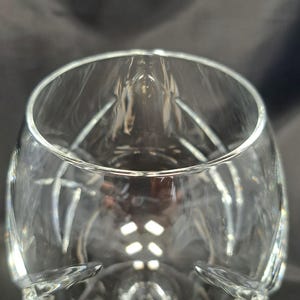 Puede incluir: Una copa de cristal transparente con un cuerpo ancho y redondeado y un borde estrecho. El cristal presenta una serie de facetas verticales talladas que crean un patr&oacute;n geom&eacute;trico texturizado en la superficie exterior, reflejando la luz.