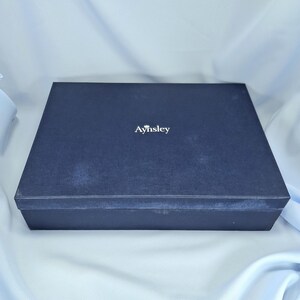 Peut inclure: Une bo&icirc;te rectangulaire bleu marine fonc&eacute; avec le mot "Aynsley" en lettres blanches. La bo&icirc;te a une surface textur&eacute;e et un design simple et &eacute;l&eacute;gant, adapt&eacute; au stockage ou au cadeau.