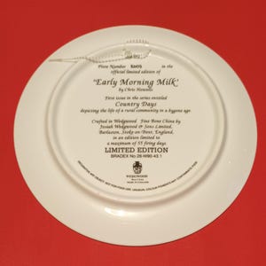 Pode incluir: Um prato de cer&acirc;mica branca com uma borda dourada e um texto que diz "Early Morning Milk" de Chris Howells. O prato faz parte de uma s&eacute;rie de edi&ccedil;&atilde;o limitada chamada "Country Days" que representa a vida rural. &Eacute; feito em porcelana fina Wedgwood por Josiah Wedgwood & Sons Limited, Barlaston, Stoke-on-Trent, Inglaterra. O prato &eacute; limitado a um m&aacute;ximo de 55 dias de cozedura e tem um n&uacute;mero Bradex de 26-W90-43.1.