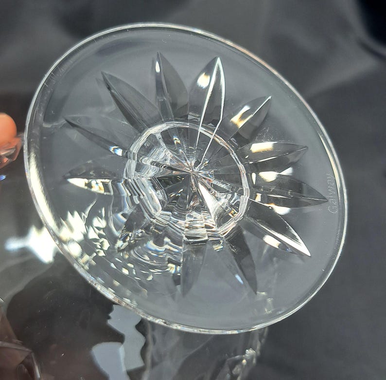 May include: A clear crystal glass base featuring a starburst pattern cut into the underside. The circular base has a faceted design radiating from the centre, with the word Galway etched into the glass surface near the outer edge of the rim.
