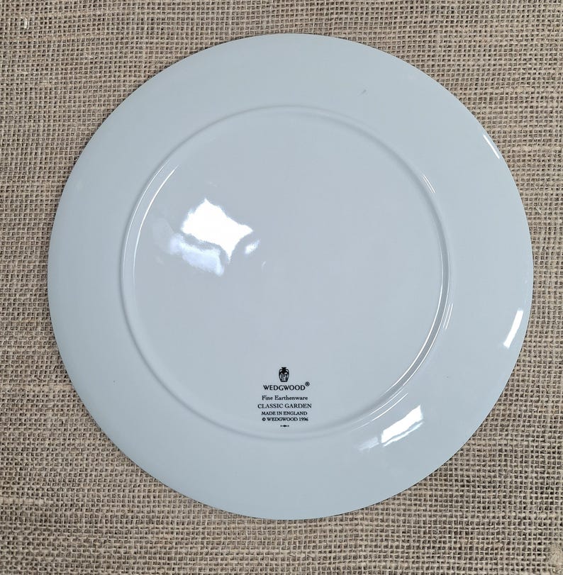 K&ouml;nnte beinhalten: Hellblaue Wedgwood Classic Garden Feinkeramik-Platte. Die Platte hat einen breiten Rand und eine leicht erh&ouml;hte Mitte. Das Wedgwood-Logo und Produktinformationen sind auf der R&uuml;ckseite aufgedruckt. Hergestellt in England.