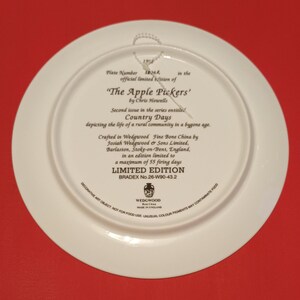Pode incluir: Um prato de cer&acirc;mica branca com uma borda dourada e uma inscri&ccedil;&atilde;o em preto e dourado. A inscri&ccedil;&atilde;o diz "The Apple Pickers' by Chris Howells" e "Country Days depicting the life of a rural community in a bygone age." O prato faz parte de uma s&eacute;rie de edi&ccedil;&atilde;o limitada, elaborada em porcelana fina Wedgwood por Josiah Wedgwood & Sons Limited, Barlaston, Stoke-on-Trent, Inglaterra. O prato &eacute; uma edi&ccedil;&atilde;o limitada de 55 dias de cozedura e tem um n&uacute;mero Bradex de 26-W90-43.2.