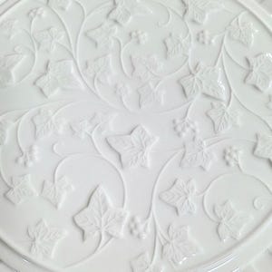 K&ouml;nnte beinhalten: Ein wei&szlig;er Keramikteller mit einem gepr&auml;gten Efeublattmuster. Die Bl&auml;tter und Ranken sind erhaben und erzeugen eine strukturierte Oberfl&auml;che. Der Teller hat einen abgerundeten Rand und ein detailliertes, von der Natur inspiriertes Muster.