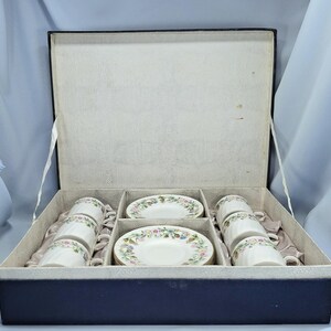 Peut inclure: Un service &agrave; th&eacute; vintage dans une bo&icirc;te bleu marine. L'ensemble comprend six tasses et soucoupes blanches, chacune d&eacute;cor&eacute;e d'un motif floral rose, jaune et bleu. L'int&eacute;rieur de la bo&icirc;te est gris clair.