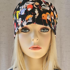 Könnte beinhalten: Eine schwarze Mütze mit einem bunten Aufdruck von Anime-Charakteren. Die Mütze ist aus weichem, dehnbarem Stoff und perfekt, um den Kopf im Winter warm zu halten.