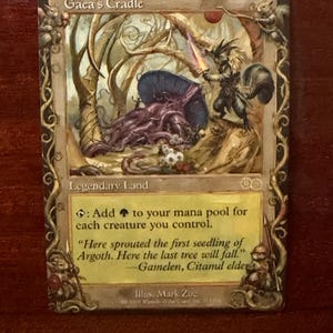 Peut inclure: Une carte à collectionner Gaea's Cradle illustrée d'un guerrier écureuil armé d'une épée près d'un grand champignon violet. Le texte de la carte inclut 'Legendary Land', 'Add green mana to your mana pool' et une citation de Gamelen, Citamul elder.