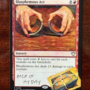 May include: A red Magic: The Gathering card titled "Blasphemous Act" with artwork of hands holding a deck of cards. The card text includes the spell's cost and effect. Handwritten text on the card reads "BACK IN MY DAY."