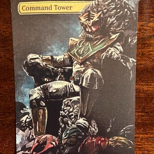 May include: A fantasy-style illustration of a green and black armored figure sitting on a throne. The figure is wearing a helmet with a red visor and a cape. The figure is surrounded by other figures, some of which are lying on the ground. The text "Command Tower" is at the top of the image.