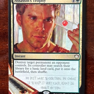 May include: A Magic: The Gathering card titled "Assassin's Trophy." The card features a portrait of a man holding a small object. Text on the card includes game instructions and the phrase "THE BEST WAY TO CONTROL THE CHOAS IS TO KEEP IT VERY CLOSE, RIGHT IN FRONT OF YOU."