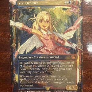 May include: A Magic: The Gathering card featuring Vivi Ornitier, a Legendary Creature Wizard. The card has a colorful illustration of a female character with blonde hair and a pink dress. The card's text details its abilities and mana costs.