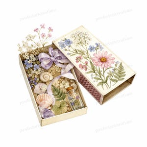 Op de afbeelding: Een rechthoekige doos met een bloemenillustratie op het deksel, gevuld met geperste bloemen, een lavendelkleurig lint, schelpen, een klein kristal en een piepklein glazen flesje met gedroogde bloemen. De binnenkant is gevuld met botanische elementen.