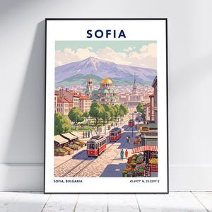Puede incluir: Un póster enmarcado con una colorida ilustración de Sofía, Bulgaria. La obra de arte representa una calle de la ciudad con tranvías rojos, edificios y una montaña al fondo. La palabra "SOFIA" está en la parte superior.