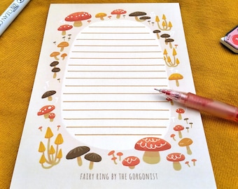May include: A white notepad with a mushroom border. The notepad has lined paper and the text "Fairy Ring by the Gorgonist" at the bottom.