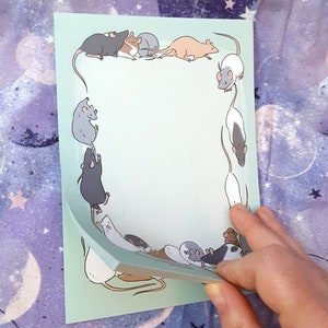 Könnte beinhalten: Ein hellgrüner Notizblock mit einem Rand aus Comic-Ratten in verschiedenen Posen. Die Ratten sind schwarz, weiß und braun. Der Notizblock ist leer und bereit zum Schreiben.