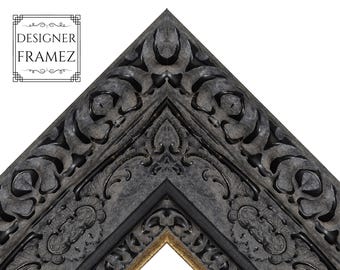 Puede incluir: Una esquina de marco de fotos gris carbón oscuro con intrincadas tallas florales y de volutas en relieve. El marco presenta un acabado profundo y texturizado con bordes interiores en tono dorado. El texto "DESIGNER FRAMEZ" es visible.