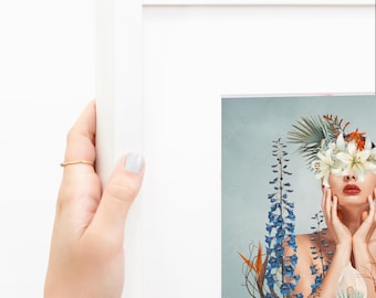 Puede incluir: Un marco de fotos blanco que contiene una impresión de una persona con flores cubriendo sus ojos. La obra presenta espuelas de caballero azules, lirios blancos y follaje naranja sobre un fondo azul pálido. El marco tiene un borde blanco.