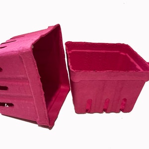 May include: Two pink paper pulp berry baskets. The baskets are square and have a textured surface. The baskets are empty.