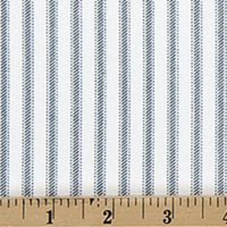 Puede incluir: Una tela blanca con un patr&oacute;n de rayas verticales azules, cada una compuesta por finas l&iacute;neas diagonales. Una regla de madera est&aacute; colocada en el borde inferior, mostrando medidas en cent&iacute;metros, con el n&uacute;mero 3 visible hacia la derecha.