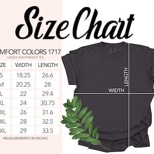 Op de afbeelding: Een donkergrijs Comfort Colors 1717 unisex heavyweight t-shirt met een maattabel. De maattabel toont afmetingen in inches voor maten S t/m 4XL. Het shirt heeft een groene blad tak in de hoek.