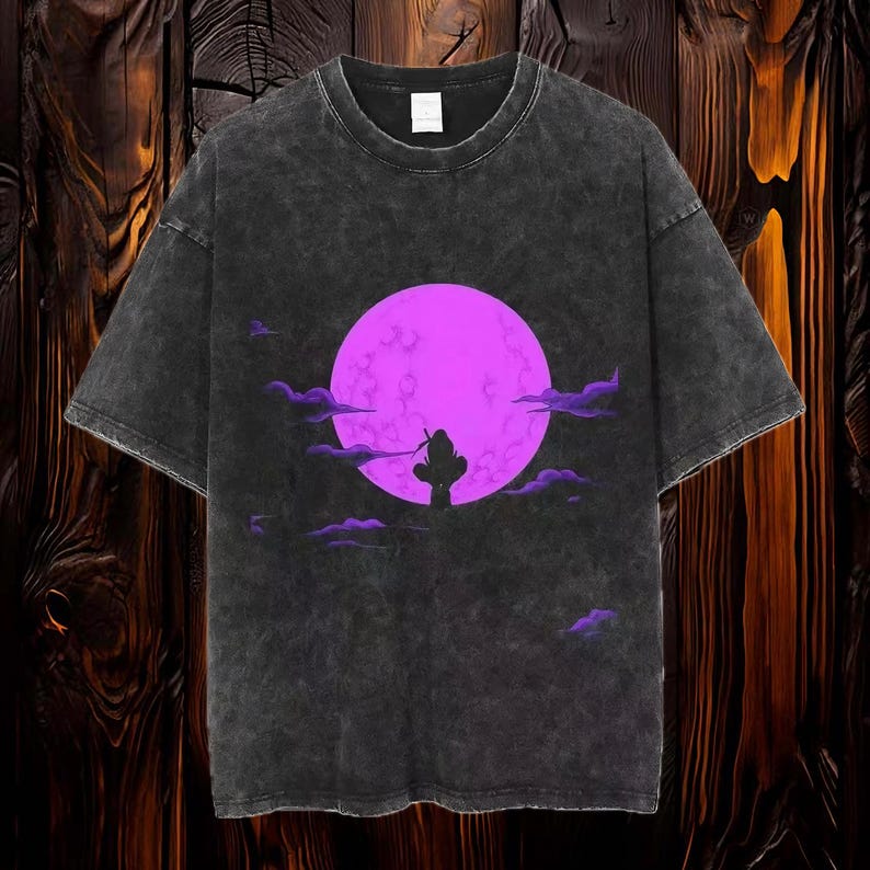 May include: A black t-shirt with a faded look features a silhouette of a person standing in front of a large, bright purple moon. The moon is surrounded by clouds.