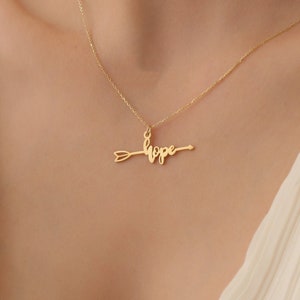 May include: A gold necklace with a pendant that says "hope" with an arrow through the word.