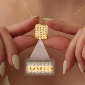 May include: Gold necklace with a square pendant featuring a word search puzzle. The words "HEJREESE ISABELLA GMACCOAS" are hidden within the puzzle.