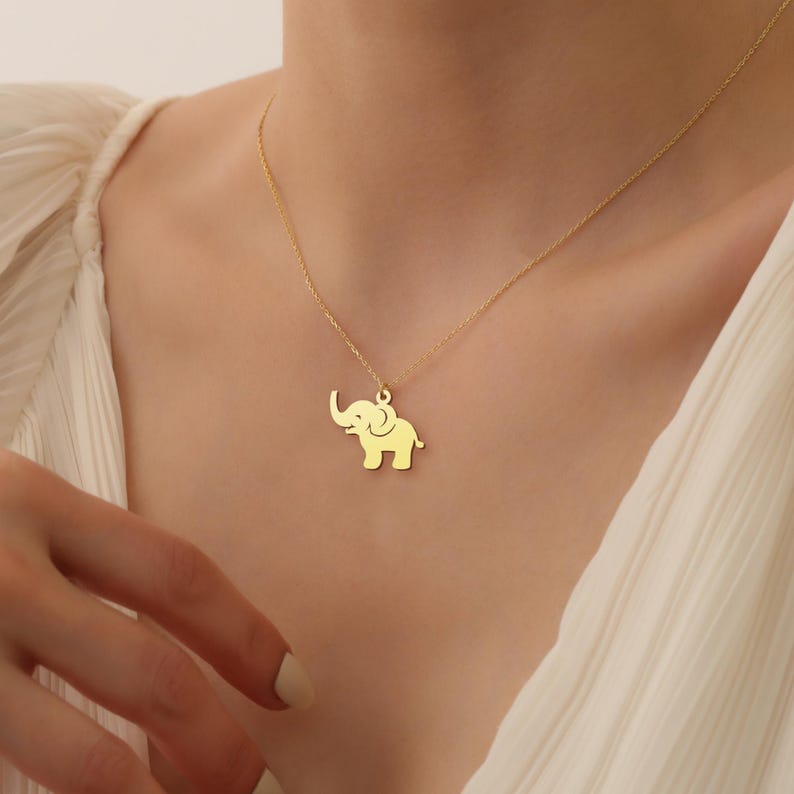 May include: A gold chain necklace with a small, gold elephant pendant.