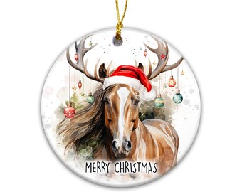 May include: A round ceramic Christmas ornament featuring a brown horse with a white blaze on its face, wearing a red and white Santa hat. The horse has large antlers decorated with hanging colorful baubles. The text MERRY CHRISTMAS is printed below.